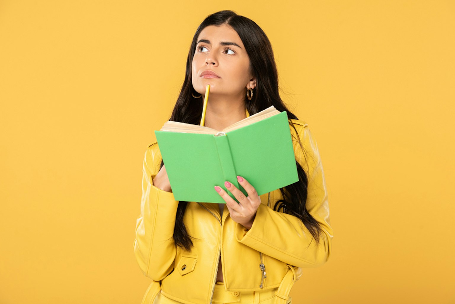 Female holding book while holding pencil against chin