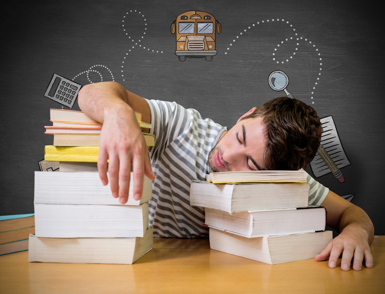 Student sleeping with head and arms on books