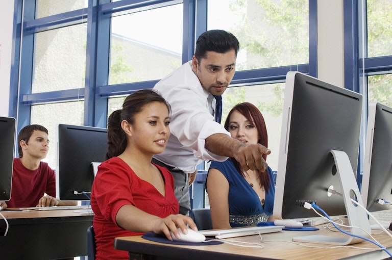 Male helping females on a computer