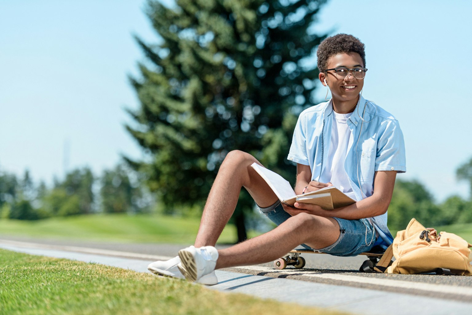 Male sitting on a skateboard while reading
